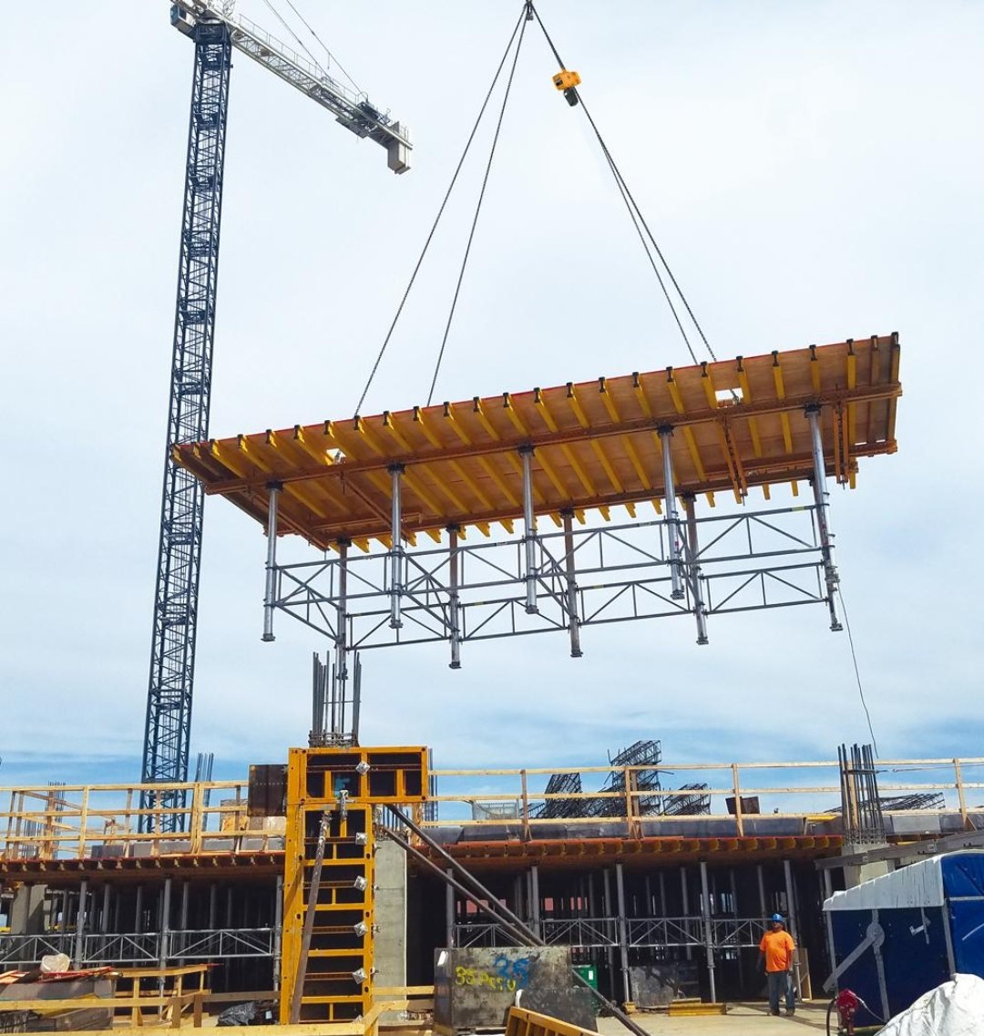 Crane lifting a formwork table on a high-rise
